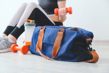 Genç kadın ışık duvarına karşı yerde antrenman yapıyor.