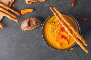 Koyu arkaplanda bir kase havuç kremalı çorba.