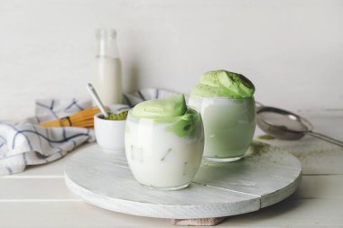 Bir tepsi lezzetli dalgona matcha latte ve hafif ahşap arka planda pudra