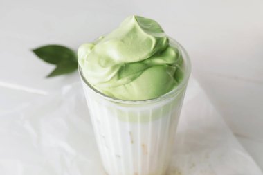 Bir bardak lezzetli dalgona matcha latte hafif ahşap arka planda, yakın plan