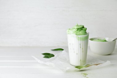 Hafif ahşap arka planda bir bardak lezzetli dalgona matcha latte.