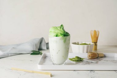 Hafif arkaplanda bir bardak lezzetli dalgona matcha latte ile kompozisyon