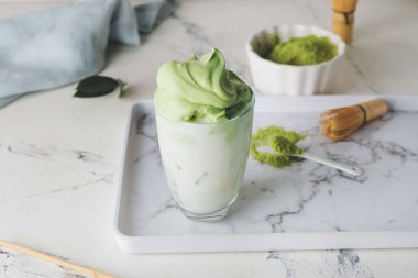 Hafif arkaplanda bir bardak lezzetli dalgona matcha latte ile kompozisyon