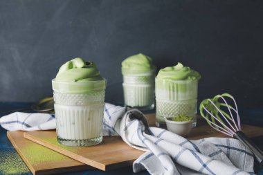Lezzetli dalgona matcha latte ile koyu arkaplanda kompozisyon