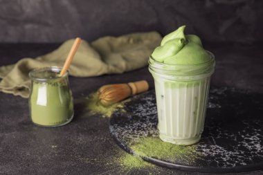Lezzetli dalgona matcha latte ile koyu arkaplanda kompozisyon