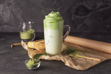 Lezzetli dalgona matcha latte ile koyu arkaplanda kompozisyon