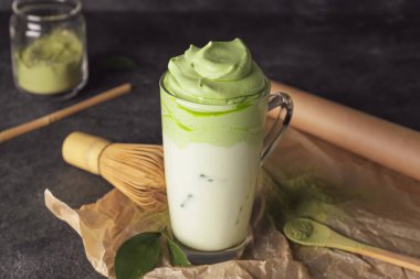 Lezzetli dalgona matcha latte ile koyu arkaplanda kompozisyon
