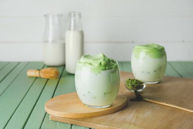 Renkli ahşap arka planda lezzetli dalgona matcha latte ile kompozisyon