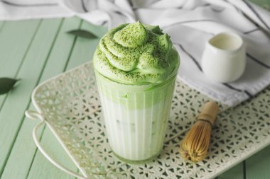 Renkli ahşap arka planda lezzetli dalgona matcha latte ile kompozisyon