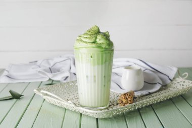 Renkli ahşap arka planda lezzetli dalgona matcha latte ile kompozisyon