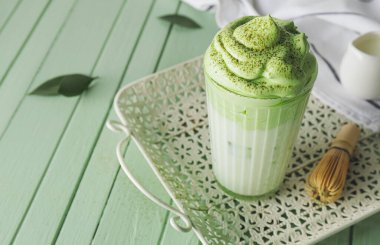 Renkli ahşap arka planda lezzetli dalgona matcha latte ile kompozisyon, yakın plan