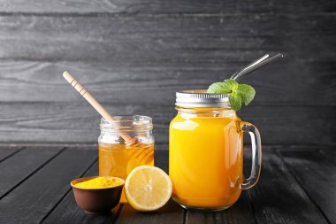 Mason kavanozu koyu ahşap arka planda sağlıklı zerdeçal içeceği.