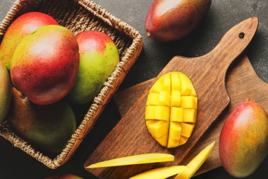 Koyu arkaplanda tatlı olgun mangoları olan kompozisyon, yakın plan.