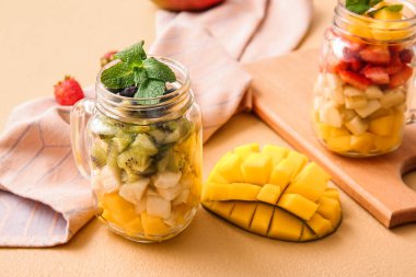 Arka planda tropikal meyve salatası olan Mason kavanozları