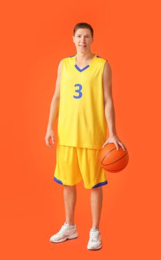 Handsome young man with ball on color background