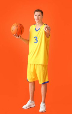 Handsome young man with ball on color background