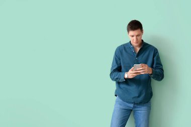 Renkli arka planda cep telefonu olan yakışıklı bir genç.