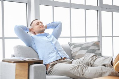 Evdeki kanepede dinlenen yakışıklı genç adam.