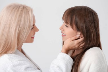 Açık arkaplanda bornozlu mutlu lezbiyen çift