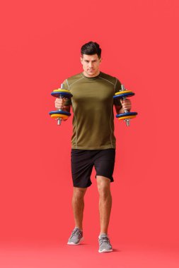 Renkli arka planda dambılları olan sportif genç adam eğitimi.