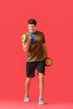 Renkli arka planda dambılları olan sportif genç adam eğitimi.