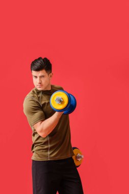 Renkli arka planda dambılları olan sportif genç adam eğitimi.