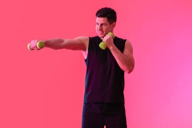 Renkli arka planda dambılları olan sportif genç adam eğitimi.