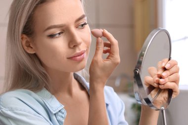 Süngerli güzel bir kadın evde makyaj yapıyor.