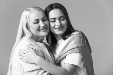 Gri arkaplanda genç kadın ve annesinin siyah beyaz portresi.