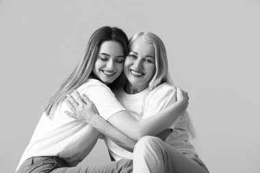 Gri arkaplanda genç kadın ve annesinin siyah beyaz portresi.