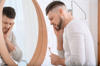 Sabah dişlerini fırçalarken acı çeken bir adam.