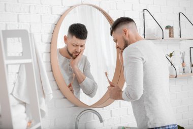 Sabah dişlerini fırçalarken acı çeken bir adam.