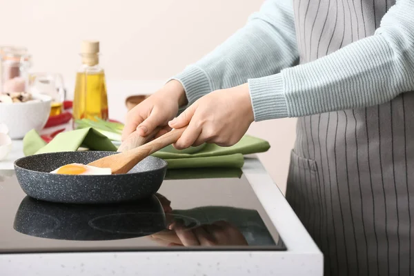 Kadın mutfakta yumurta pişiriyor.