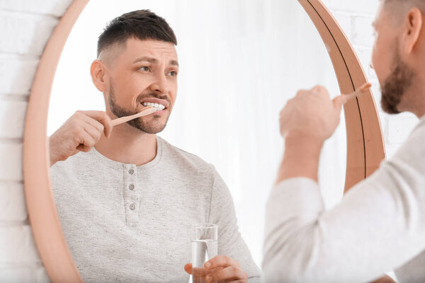 Man suffering from pain while brushing teeth in morning