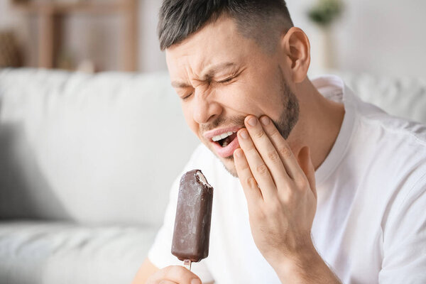 Man with sensitive teeth and ice-cream at home