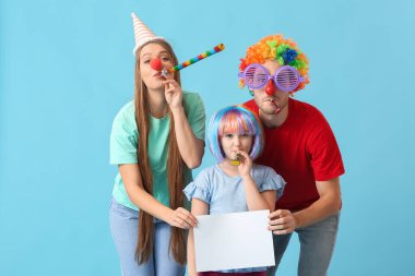 Komik kılık değiştirmiş genç bir aile ve renkli arka planda boş kağıt kağıtları var. 1 Nisan şakası