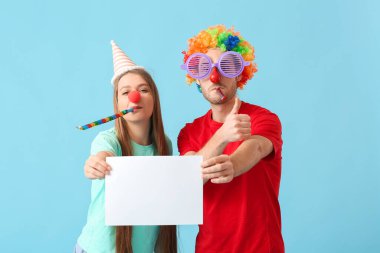 Komik kılık değiştirmiş genç bir çift ve renkli arka planda boş kağıt kağıtları var. 1 Nisan şakası