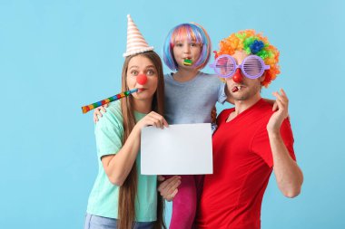 Komik kılık değiştirmiş genç bir aile ve renkli arka planda boş kağıt kağıtları var. 1 Nisan şakası