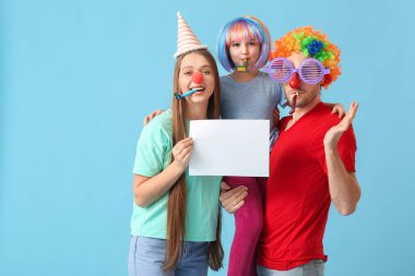 Komik kılık değiştirmiş genç bir aile ve renkli arka planda boş kağıt kağıtları var. 1 Nisan şakası