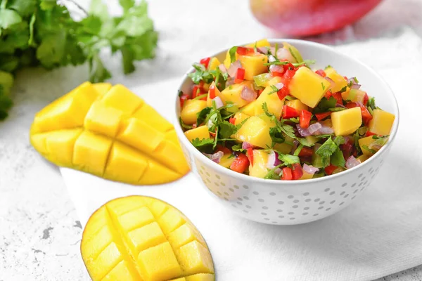 Bowl with fresh mango salsa on light background, closeup