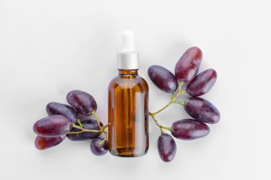 Beyaz arka planda bir şişe üzüm tohumu yağı.