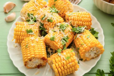 Renkli ahşap arka planda lezzetli fırında mısır koçanları olan tabak.