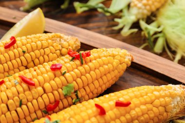 Ahşap arka planda lezzetli mısır koçanları olan tahta.