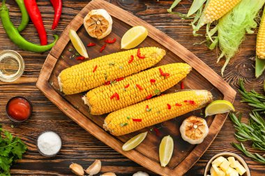 Lezzetli mısır koçanı ve ahşap arka planda sarımsak olan bir tahta.
