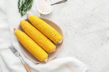 Hafif arka planda lezzetli fırınlanmış mısır koçanı tabağı.