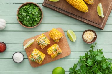 Renkli ahşap arka planda lezzetli, fırında mısır koçanları olan tahta.