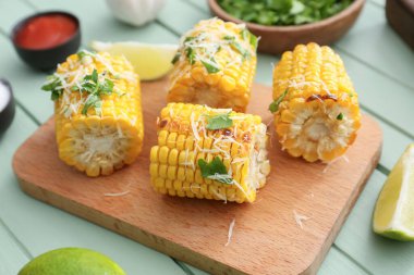 Renkli ahşap arka planda lezzetli, fırında mısır koçanları olan tahta.