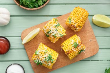Renkli ahşap arka planda lezzetli, fırında mısır koçanları olan tahta.