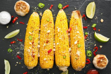 Lezzetli mısır koçanı ve koyu arkaplanda sarımsak.