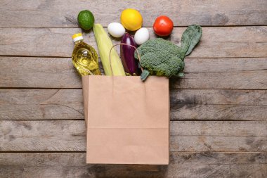 Tahta zemin üzerinde farklı ürünler olan kağıt torba.